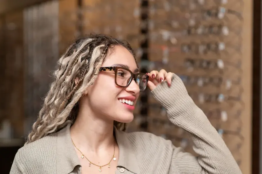 A patient smiling while trying on frames at the TSO Kyle optical gallery